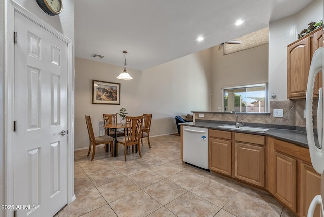 kitchen featuring visible vents, a sink, decorative backsplash, stainless steel dishwasher, and dark countertops