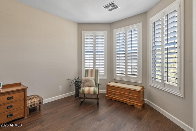 sitting room with visible vents, baseboards, and dark wood finished floors