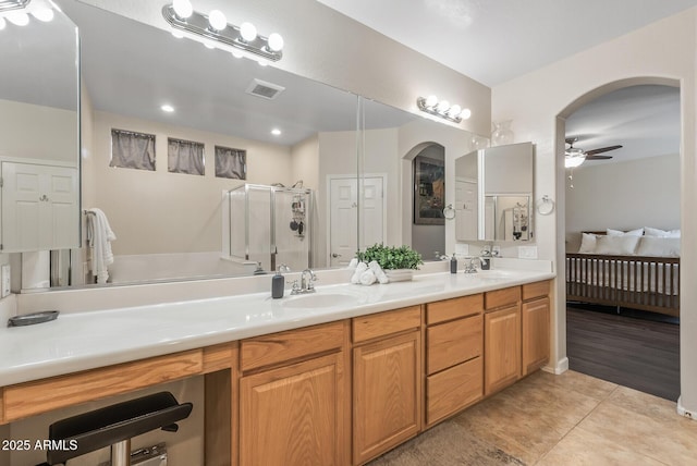 ensuite bathroom with visible vents, a stall shower, a sink, tile patterned flooring, and ceiling fan