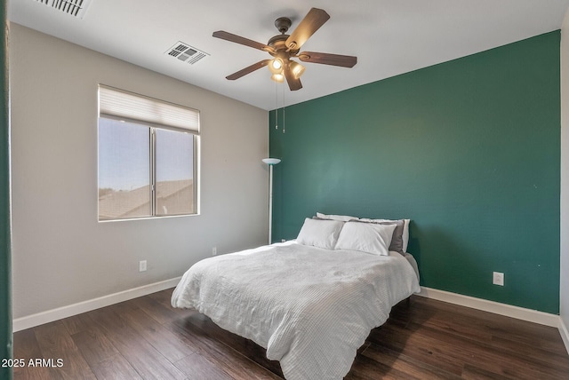 bedroom with wood finished floors, visible vents, and baseboards