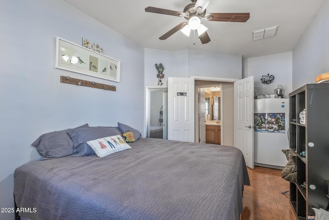 tiled bedroom with connected bathroom, visible vents, and ceiling fan