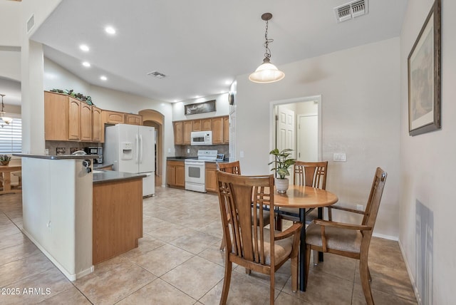 kitchen with white appliances, tasteful backsplash, arched walkways, and visible vents