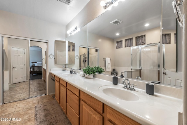 bathroom with a sink, visible vents, a shower with door, and double vanity