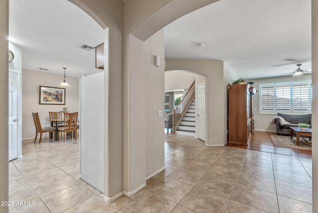 corridor featuring stairs, light tile patterned floors, baseboards, and visible vents