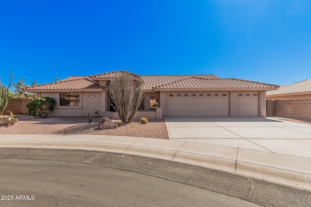 view of front facade featuring a garage, driveway, a tile roof, fence, and stucco siding