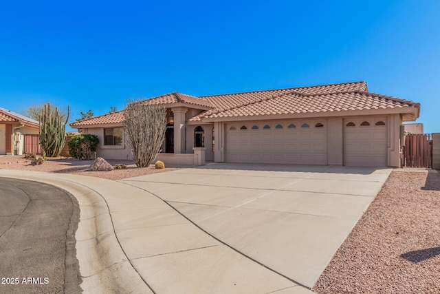 mediterranean / spanish-style home with concrete driveway, a tile roof, an attached garage, fence, and stucco siding