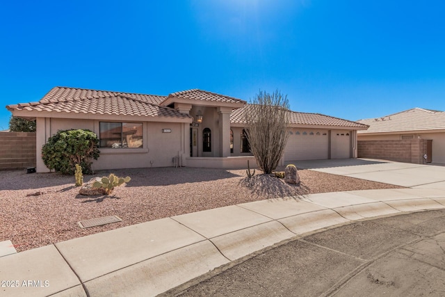 view of front facade with a tiled roof, fence, driveway, and stucco siding