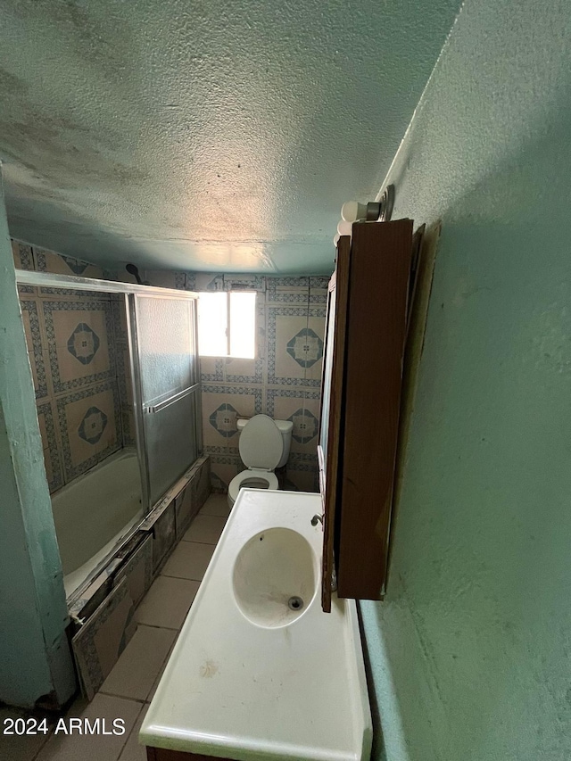 full bathroom with enclosed tub / shower combo, sink, toilet, and a textured ceiling