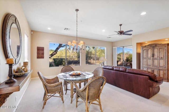 dining room with light carpet and ceiling fan with notable chandelier