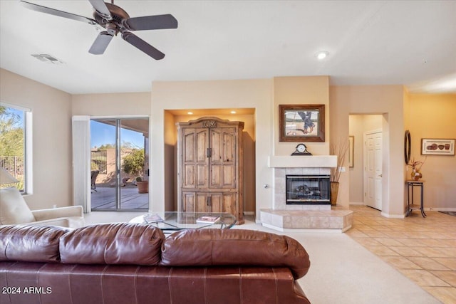 tiled living room with a wealth of natural light, ceiling fan, and a fireplace