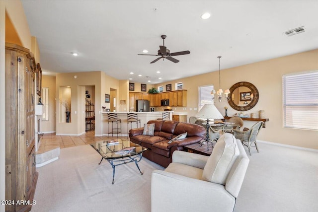 tiled living room with ceiling fan with notable chandelier and a wealth of natural light