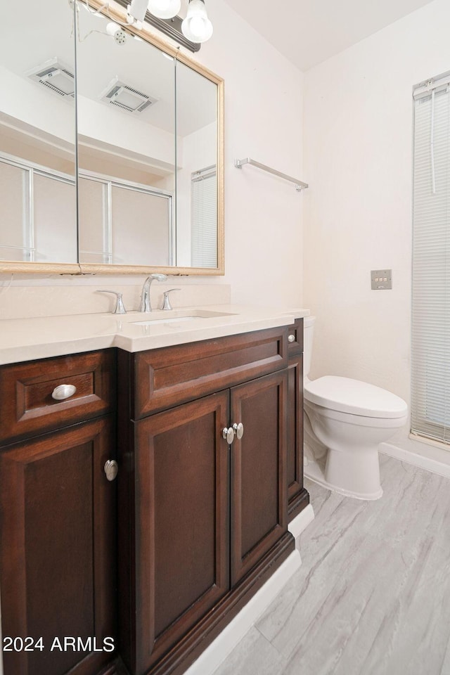 bathroom featuring vanity, hardwood / wood-style flooring, toilet, and walk in shower