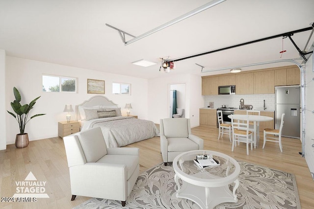 bedroom with light hardwood / wood-style floors and stainless steel fridge with ice dispenser