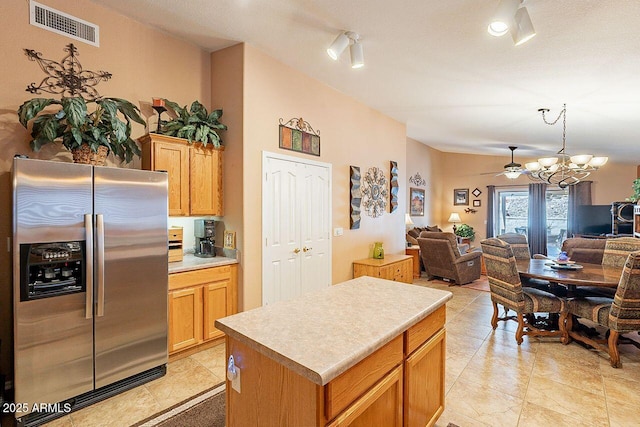 kitchen with light countertops, open floor plan, visible vents, and stainless steel fridge