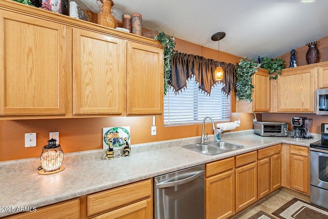 kitchen featuring a toaster, a sink, light countertops, appliances with stainless steel finishes, and pendant lighting