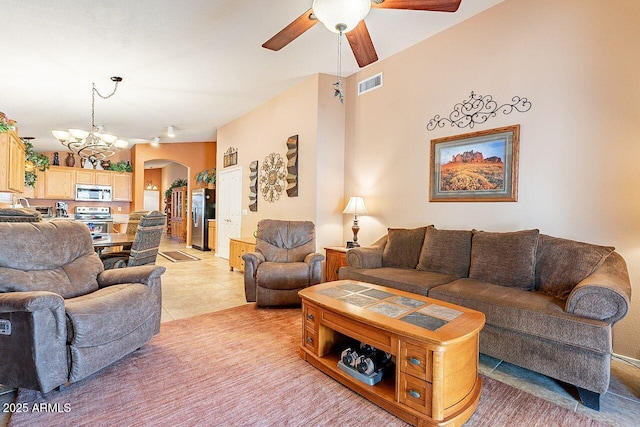 living area with visible vents, light tile patterned floors, ceiling fan with notable chandelier, and arched walkways