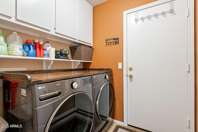 laundry area featuring baseboards, cabinet space, and separate washer and dryer