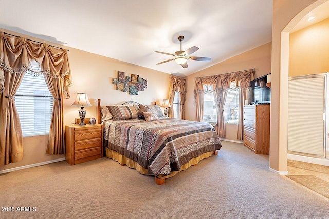 bedroom featuring light carpet, lofted ceiling, a ceiling fan, arched walkways, and baseboards