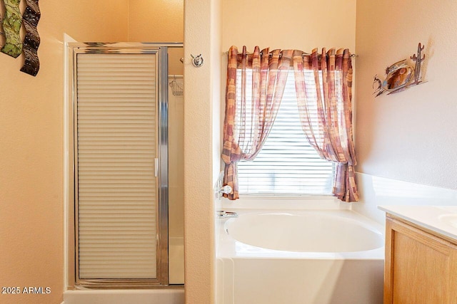 bathroom with a garden tub, a stall shower, and vanity