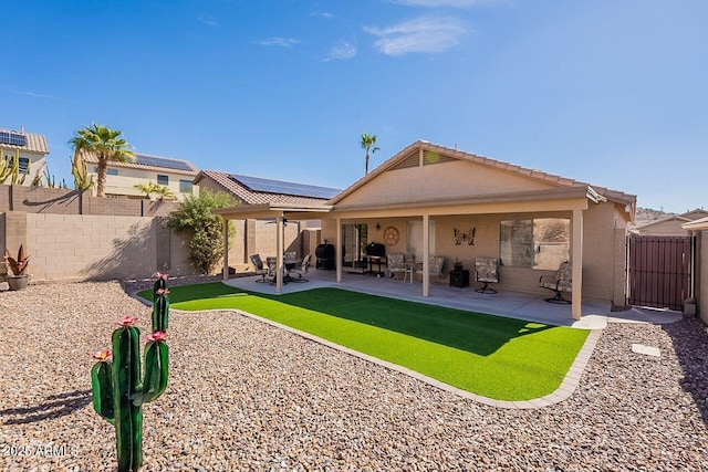 rear view of house with stucco siding, a fenced backyard, and a patio area