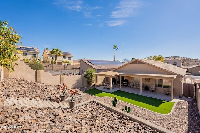 back of property with a fenced backyard, a tile roof, and a patio