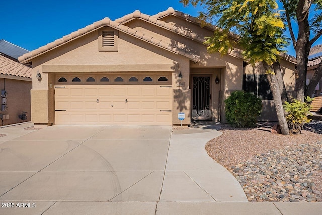 view of front of house featuring concrete driveway, a tiled roof, an attached garage, and stucco siding