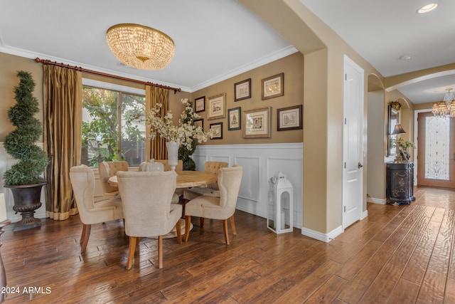 dining space featuring dark wood-type flooring, ornamental molding, and a notable chandelier