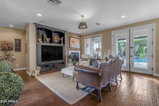 living room featuring dark wood-type flooring, plenty of natural light, french doors, and a large fireplace