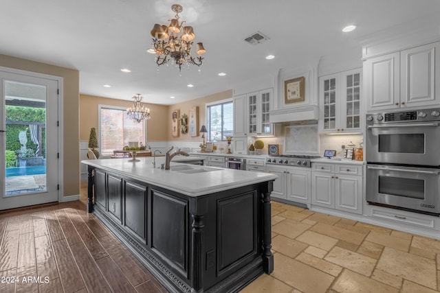 kitchen with a kitchen island with sink, stainless steel appliances, and white cabinets