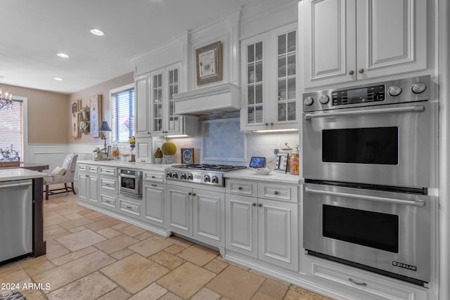 kitchen with stainless steel appliances, tasteful backsplash, a notable chandelier, and white cabinetry