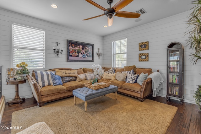 living room featuring wooden walls, ceiling fan, and dark wood-type flooring