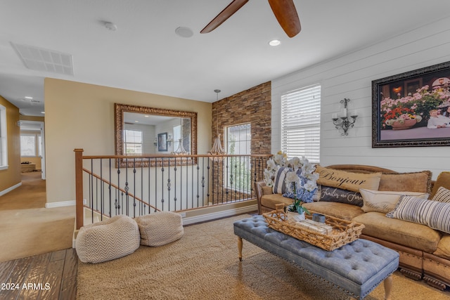 carpeted living room with wooden walls and ceiling fan