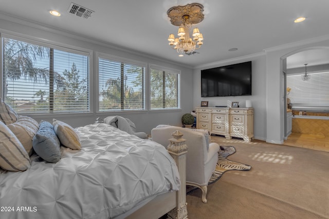 carpeted bedroom featuring a notable chandelier, ensuite bathroom, and crown molding