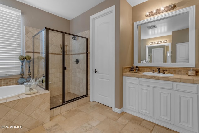 bathroom with vanity and shower with separate bathtub