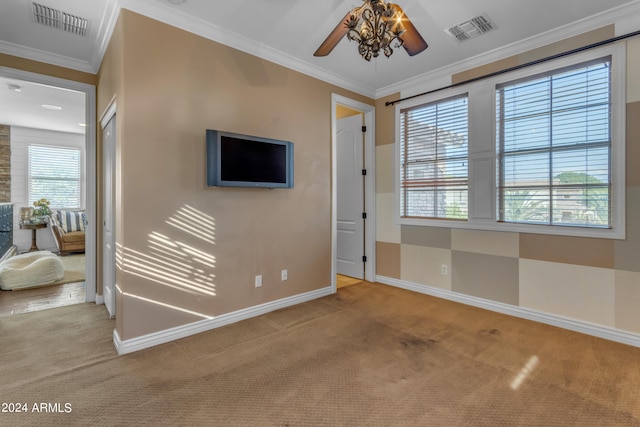 carpeted spare room featuring crown molding and ceiling fan