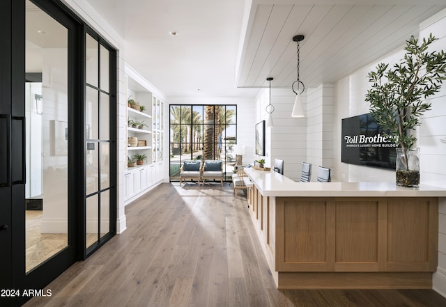 kitchen featuring a wall of windows, kitchen peninsula, pendant lighting, and wood-type flooring