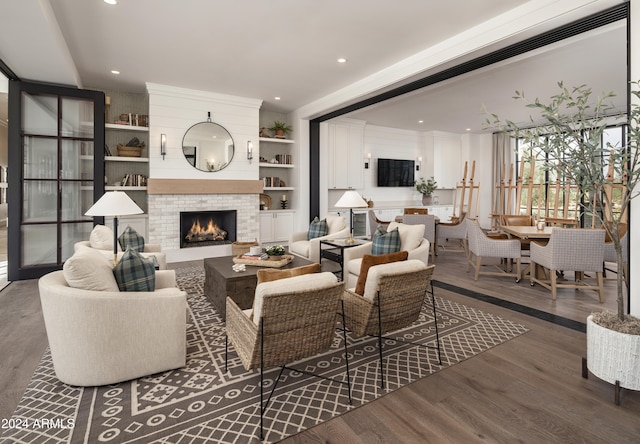 living room with built in shelves, a fireplace, and dark wood-type flooring