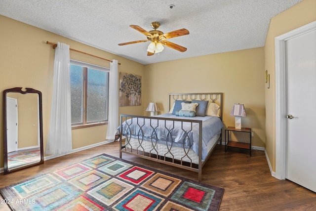 bedroom featuring dark hardwood / wood-style floors, ceiling fan, and a textured ceiling