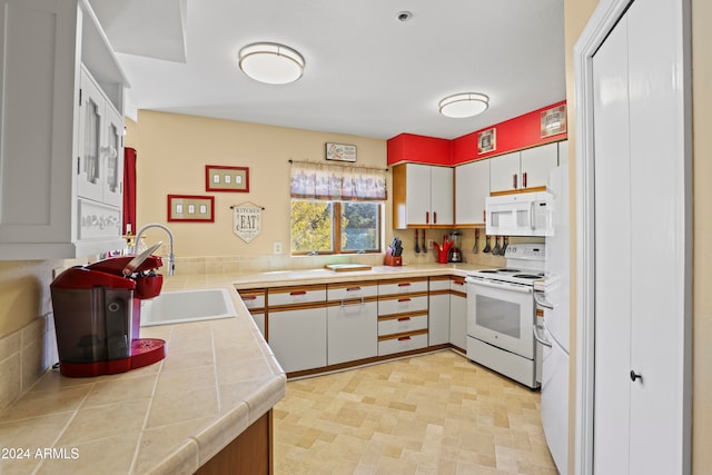 kitchen featuring kitchen peninsula, white appliances, sink, white cabinetry, and tile counters