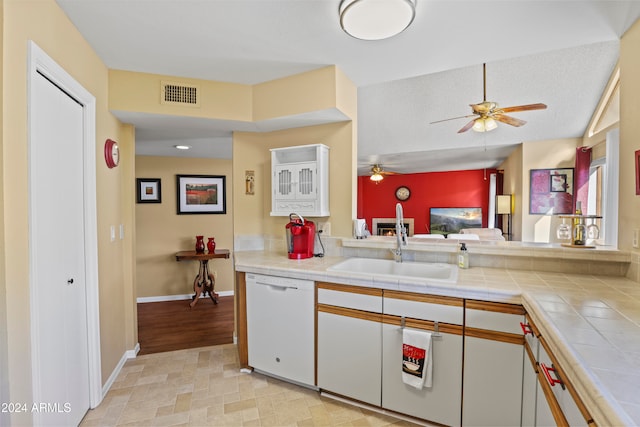 kitchen featuring white cabinetry, tile counters, sink, white dishwasher, and a textured ceiling