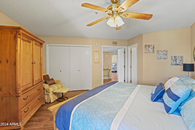 bedroom featuring a textured ceiling, a closet, ceiling fan, and dark wood-type flooring