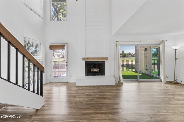 18206 N 45th Ave, Glendale, AZ 85308 - unfurnished living room with wood finished floors, a large fireplace, a high ceiling, and stairway
