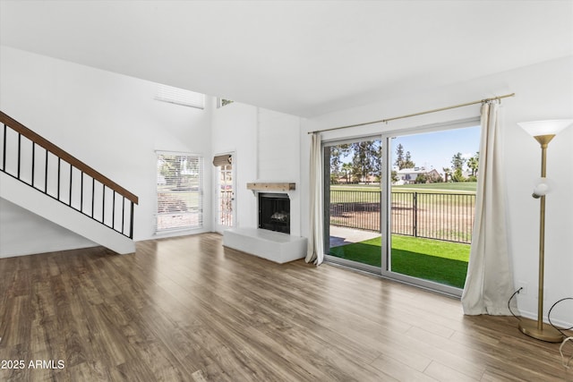 18206 N 45th Ave, Glendale, AZ 85308 - unfurnished living room featuring wood finished floors, stairway, healthy amount of natural light, and a fireplace with raised hearth