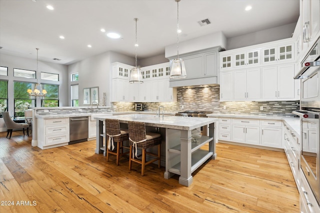 kitchen with a center island with sink, a breakfast bar, white cabinets, and decorative light fixtures