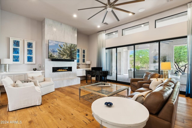 living area featuring light wood finished floors, visible vents, a high ceiling, a fireplace, and recessed lighting