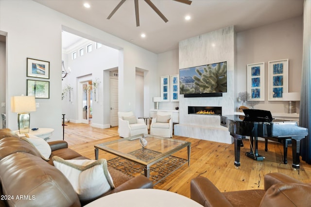 living room featuring light wood-style floors, recessed lighting, a fireplace, and a towering ceiling