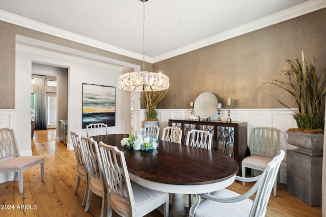 dining space with wainscoting, hardwood / wood-style flooring, crown molding, a decorative wall, and a notable chandelier