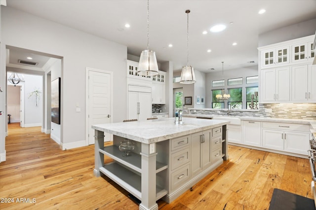 kitchen featuring a center island with sink, open shelves, visible vents, decorative backsplash, and paneled refrigerator