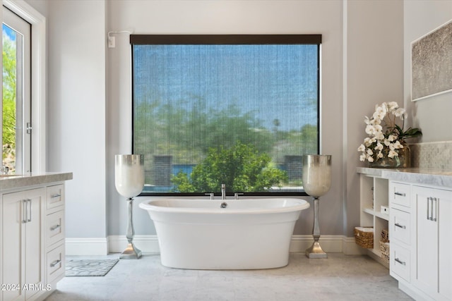 bathroom featuring a freestanding tub, baseboards, and vanity