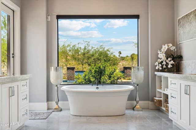 full bath featuring a soaking tub, vanity, and baseboards